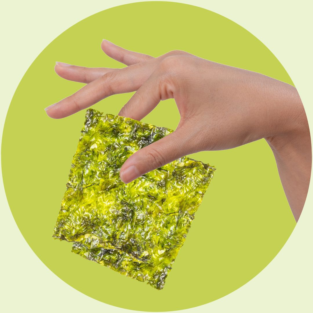 Olive oil seaweed snack held by hand on green background | Morish Snacks