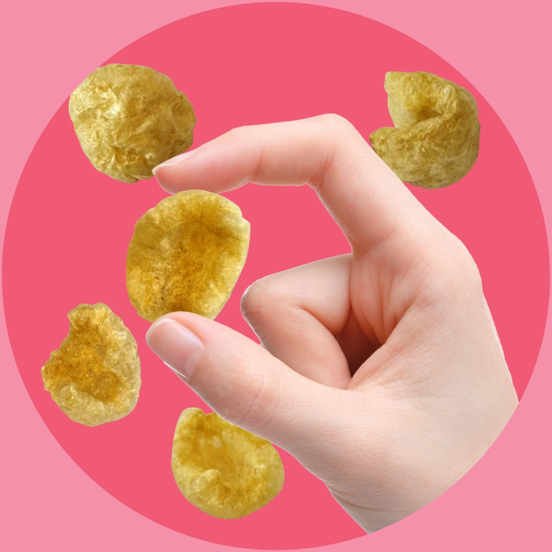 Pork snacks held by fingers on pink background | Morish Snacks