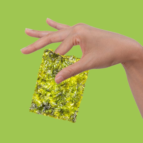 Hand holding crispy avocado oil seaweed between fingers| Morish Snacks